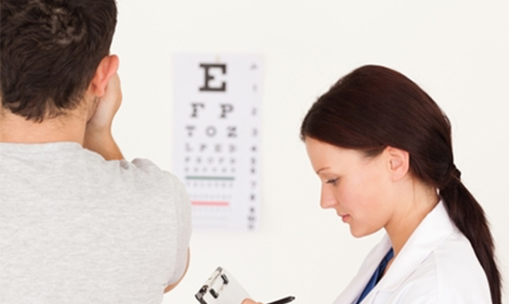 Eye chart with letters E, F, P, T, O, Z. A doctor conducts an eye exam on a patient.