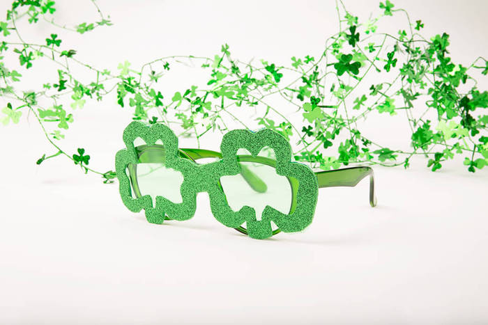 Green shamrock-shaped sunglasses with a glittery frame.