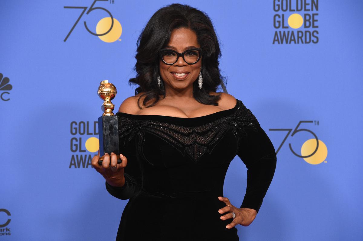 Woman holding a Golden Globe trophy, standing in front of a backdrop with &quot;75th Golden Globe Awards&quot; text.