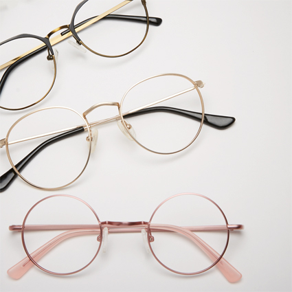 Three pairs of round eyeglasses, in black, gold, and pink frames, on a white background.