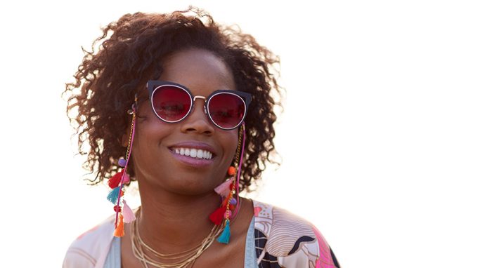 Woman wearing stylish red cat-eye sunglasses with colorful tassel earrings and layered necklaces.