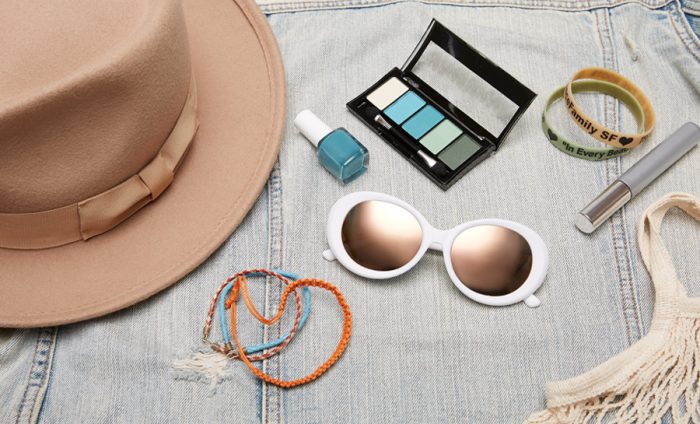 Tan hat, turquoise nail polish, eyeshadow palette, white sunglasses, colorful bracelets, lip gloss.