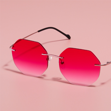 Hexagonal frameless sunglasses with gradient pink lenses on a pink background.