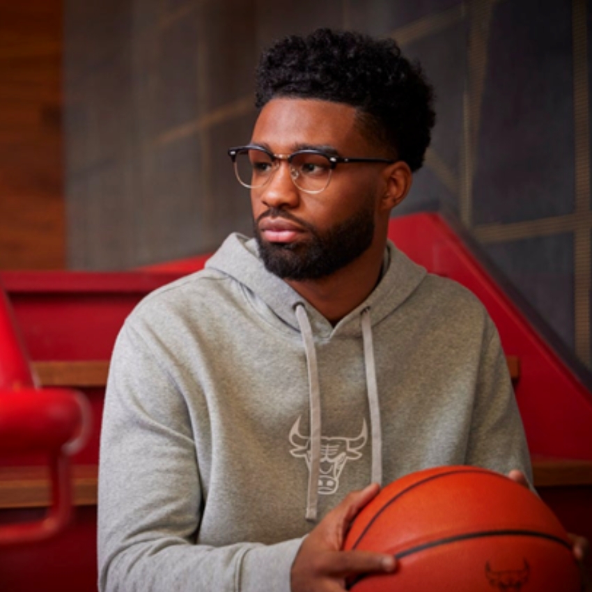 Man wearing a grey hoodie with a Chicago Bulls logo, holding a basketball.