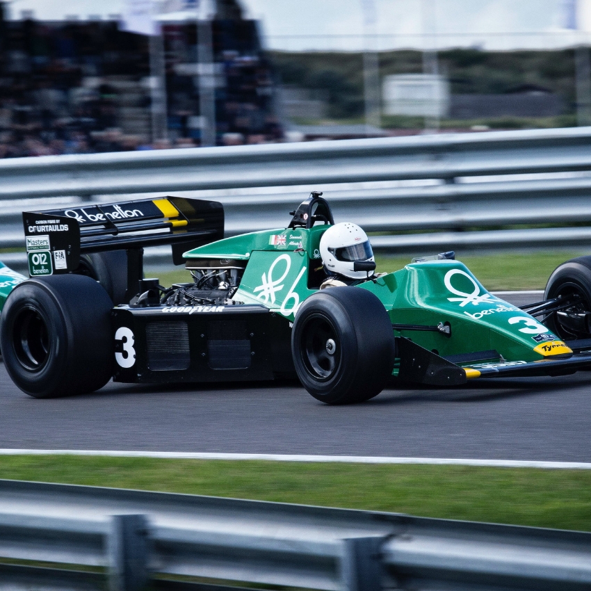 Green race car with number 3, Benetton and Goodyear logos, and driver wearing a white helmet.