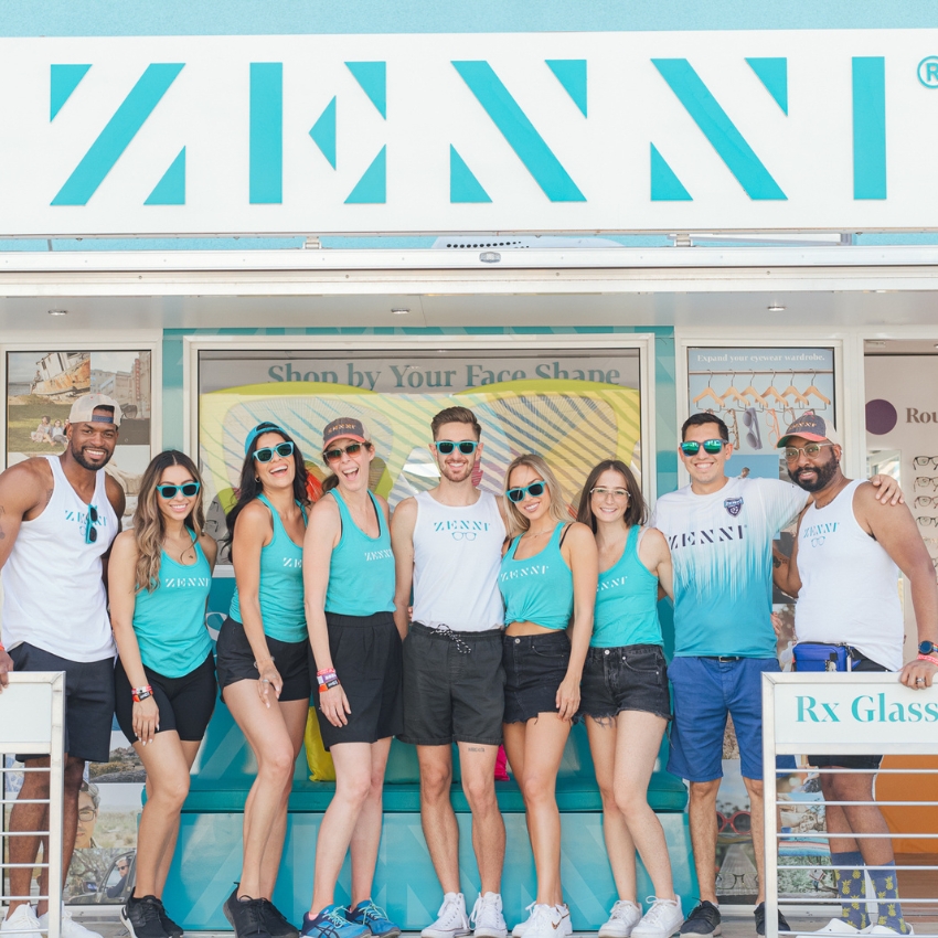 Zenni storefront with a group of people wearing Zenni branded blue and white apparel and sunglasses. Text includes "ZENNI," "Shop by Your Face Shape," "Expand your eyewear wardrobe," "Rx Glasses."