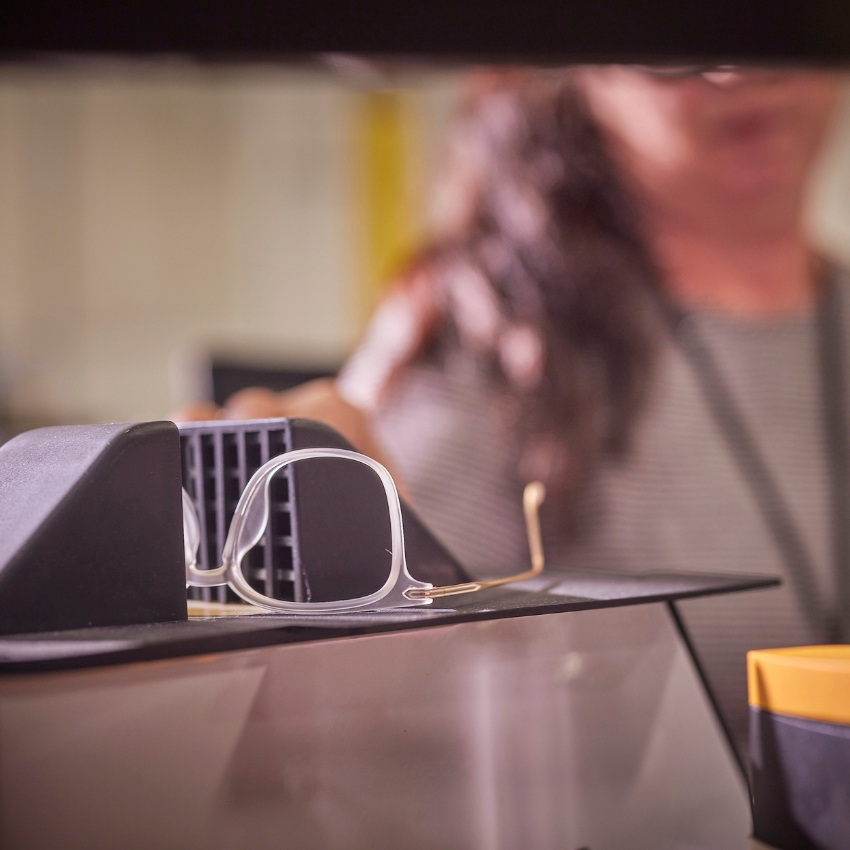 Clear-framed eyeglasses resting on a surface in front of a blurry background.