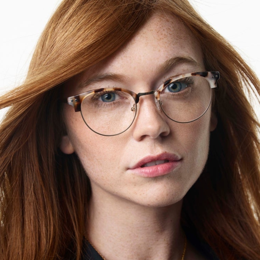 Woman wearing round tortoiseshell eyeglasses.