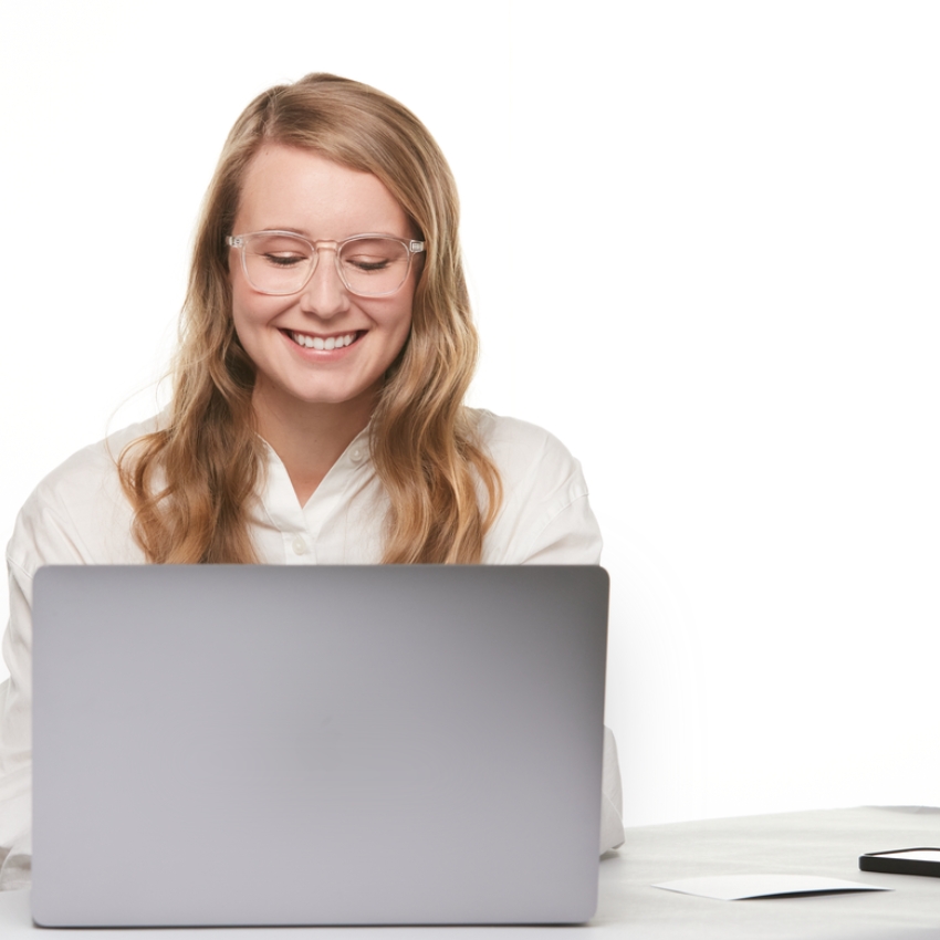 Smiling person using a silver laptop.