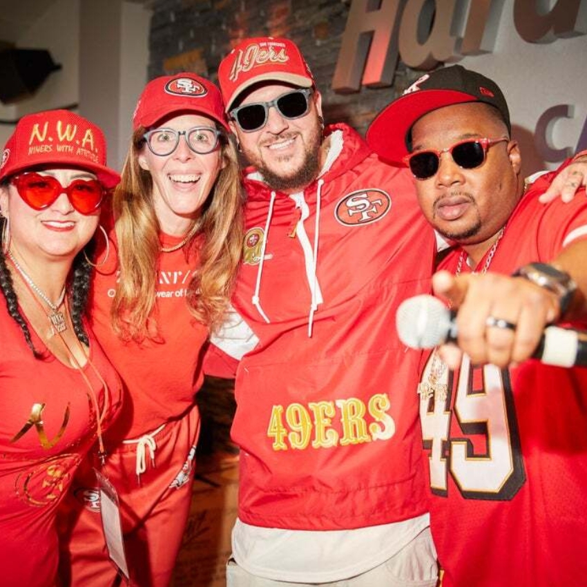 Four people in red 49ers apparel and accessories, including hats and shirts with "49ers" text and logos.