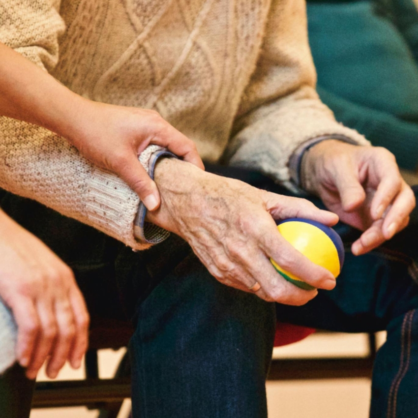 Hand holding a stress ball with another hand offering support.