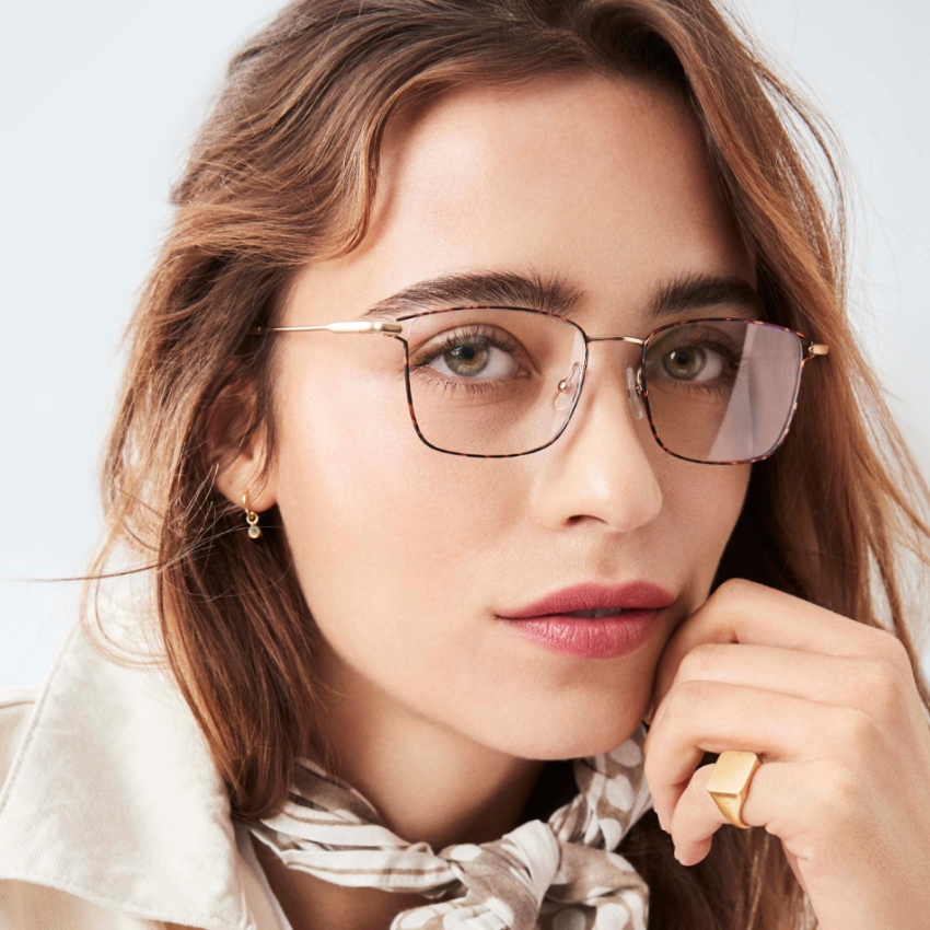 Eyeglasses with thin gold frames and rectangular lenses, worn by a female model.