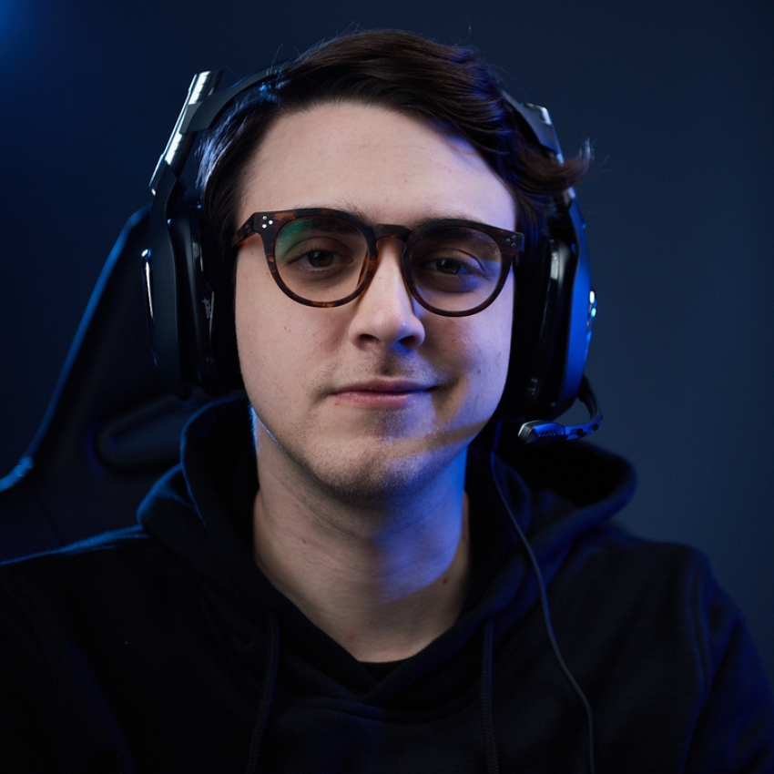 Person wearing a large headset with a microphone and glasses, dressed in a dark hoodie.