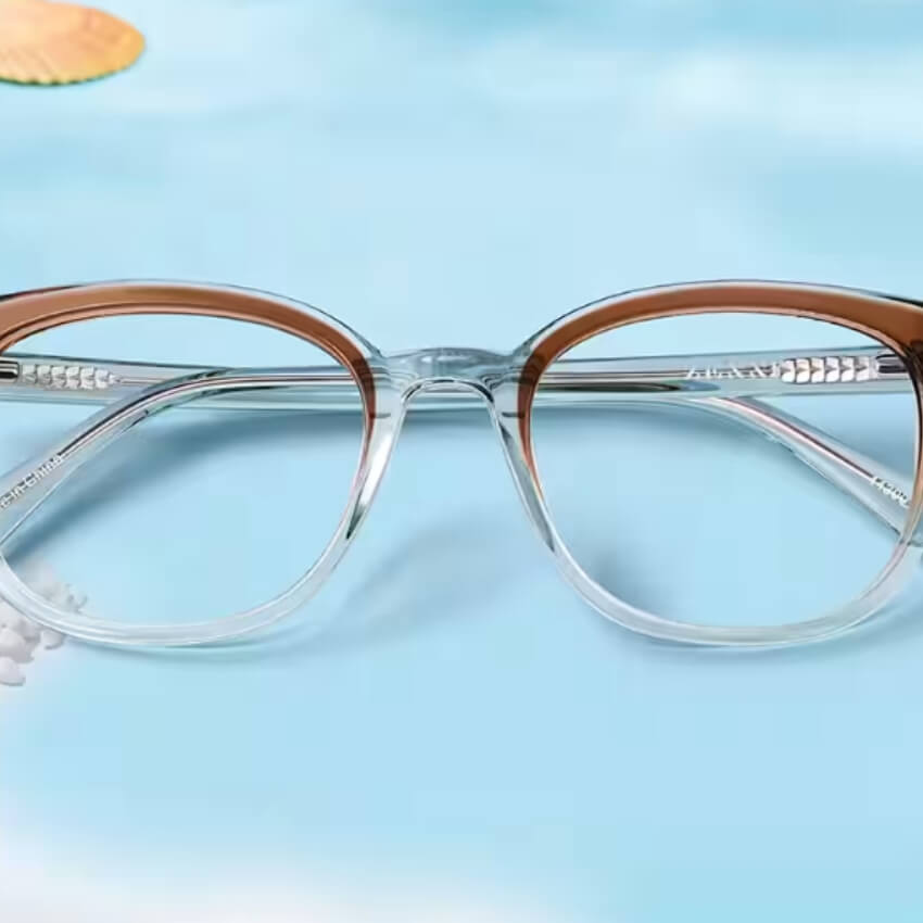 Clear eyeglasses with brown upper frames against a blue background.