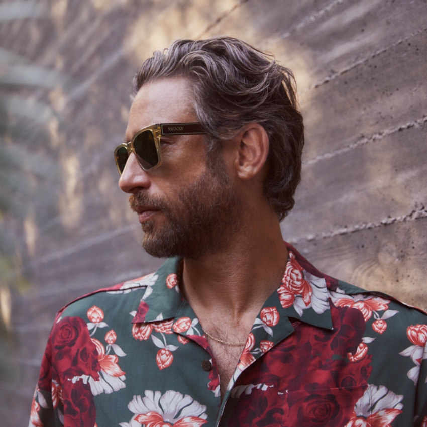 Man wearing rectangular Zegna sunglasses and a green floral print shirt.