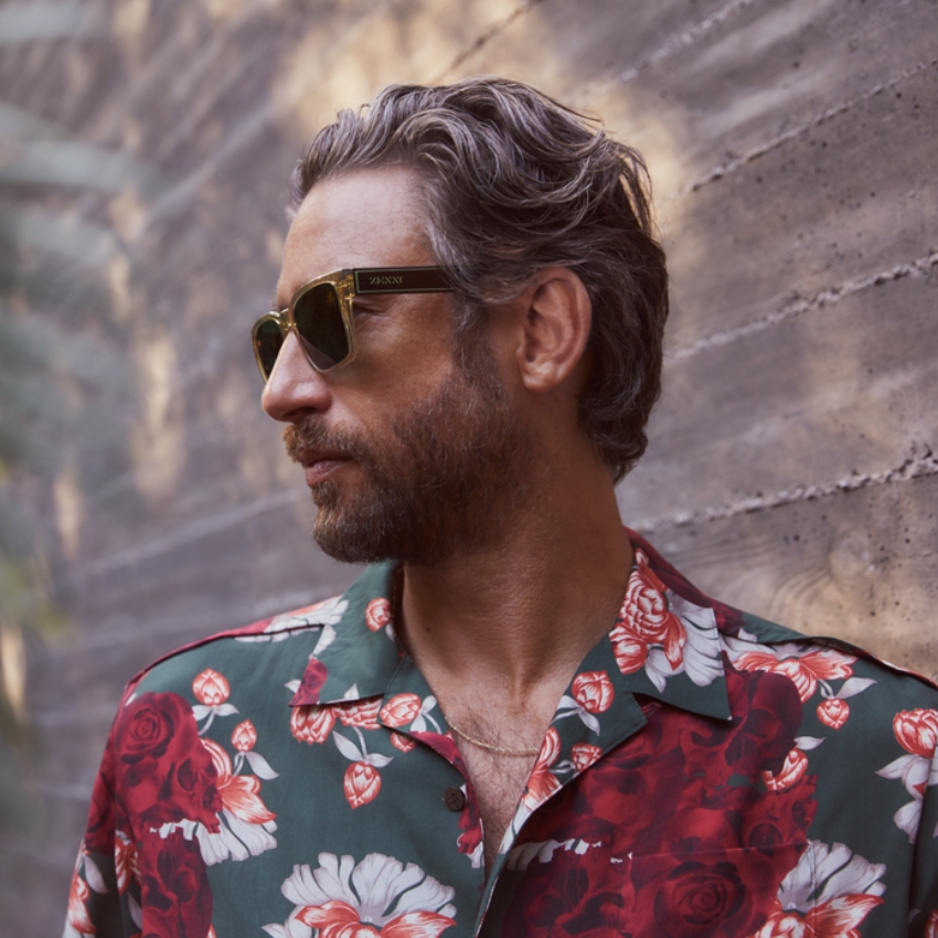 Man wearing VANNY sunglasses and a floral shirt with red and white flower patterns.