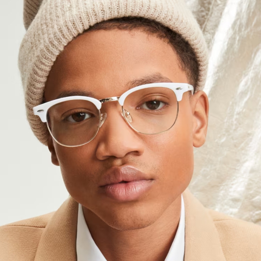 Man wearing white-rimmed eyeglasses and a beige beanie hat.