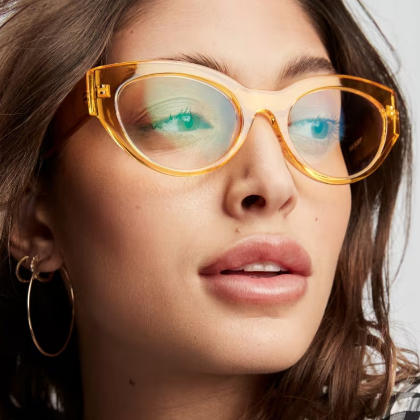 Close-up of a person wearing large, translucent yellow cat-eye glasses.