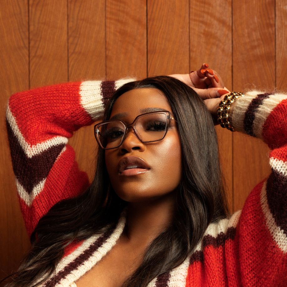 Woman wearing oversized square glasses and a red, white, and brown striped sweater.