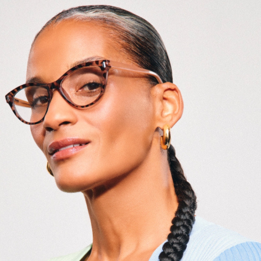 Tortoiseshell cat-eye glasses worn by a person with a sleek braided ponytail and gold hoop earrings.