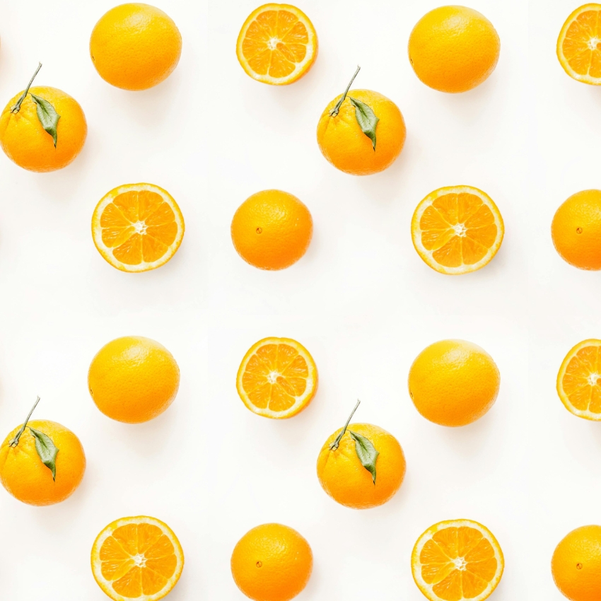 Whole and halved oranges arranged in a grid pattern. Some oranges have a green leaf attached.