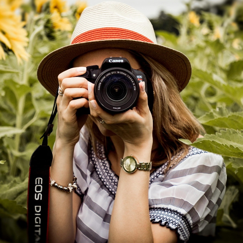 Canon EOS Digital camera with zoom lens, held by a person wearing a straw hat.