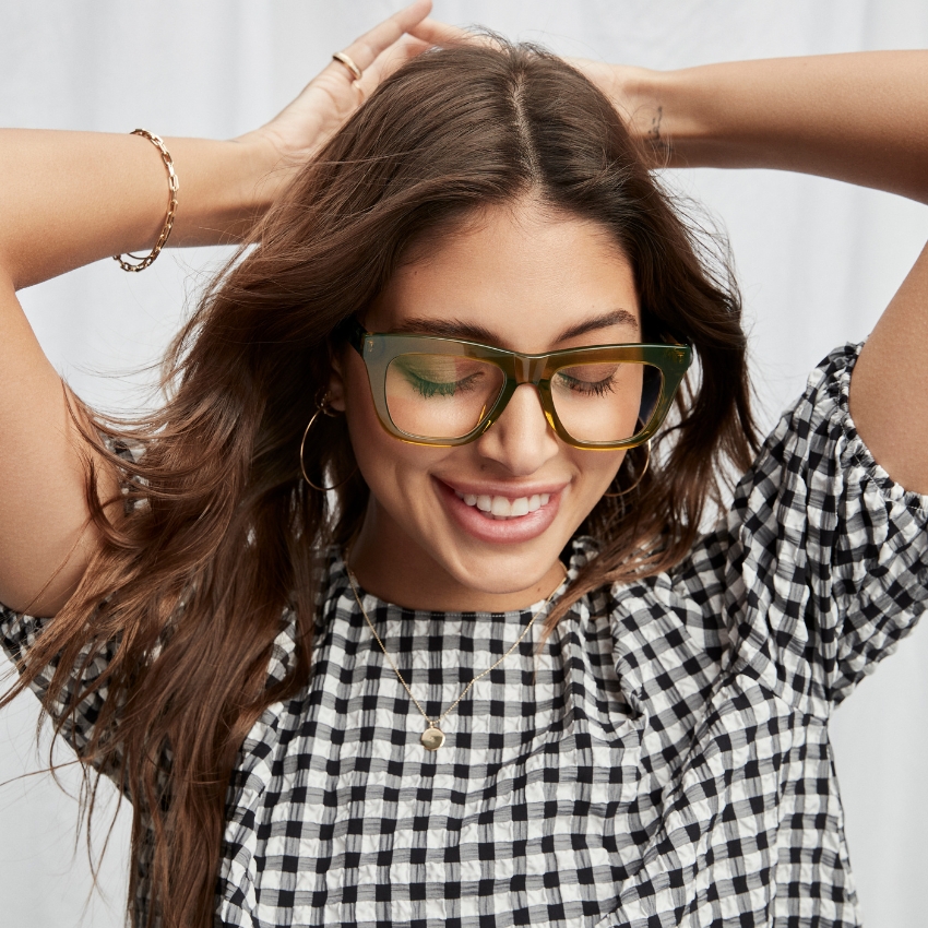 Woman wearing large, square, green eyeglasses and a black-and-white checkered top.