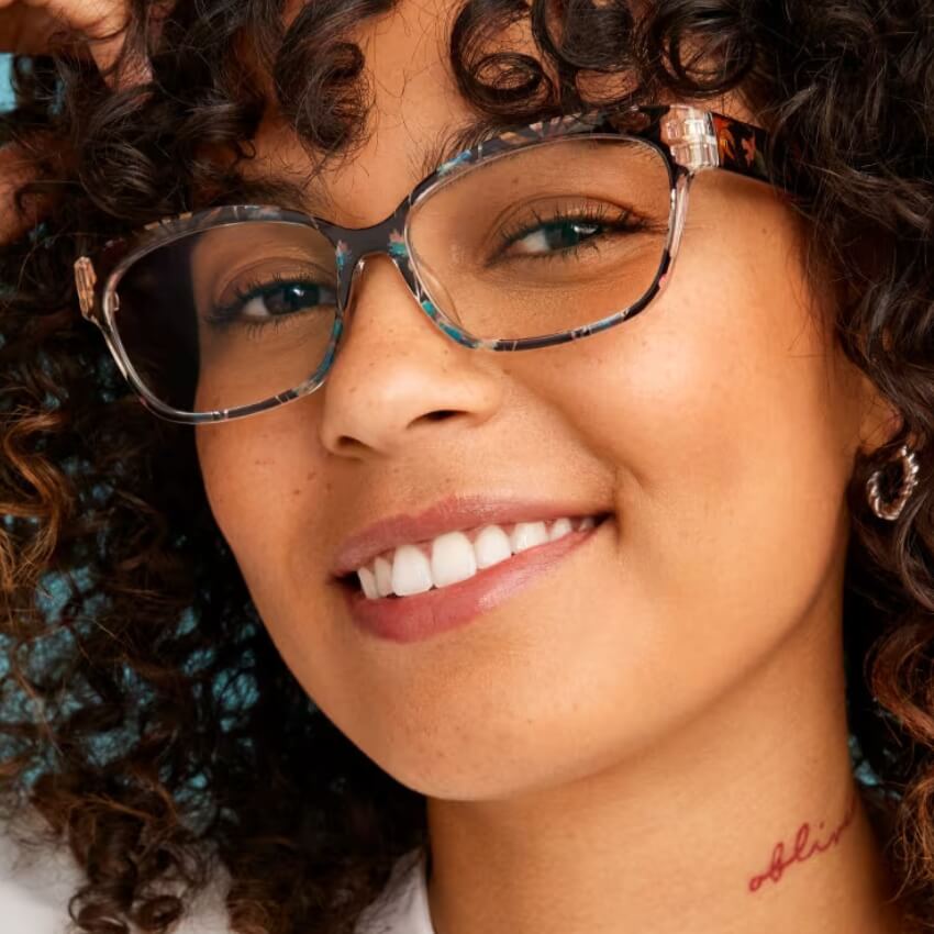 Woman wearing tortoiseshell-pattern glasses, showcasing a tattoo on her neck that reads "abis."