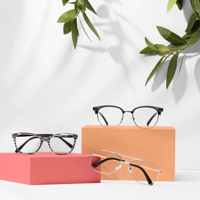 Three pairs of glasses displayed on colorful blocks, two square and one aviator-style.