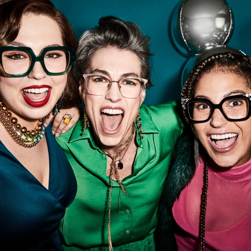 Three people wearing colorful glasses and vibrant clothing, smiling and posing energetically.