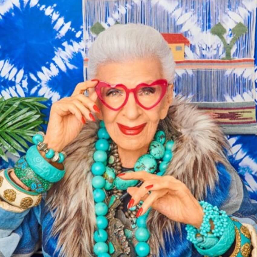 Woman wearing red heart-shaped glasses, large turquoise beaded necklace, and turquoise bracelets.