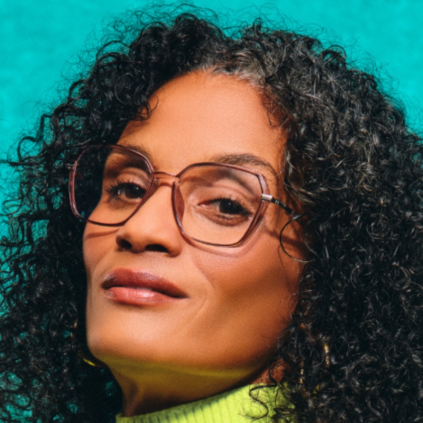 Woman with curly hair wearing large, rectangular glasses and a lime green turtleneck.