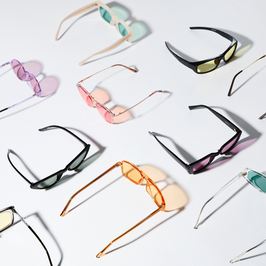 Various colorful sunglasses with different frame shapes and lens tints arranged on a white background.