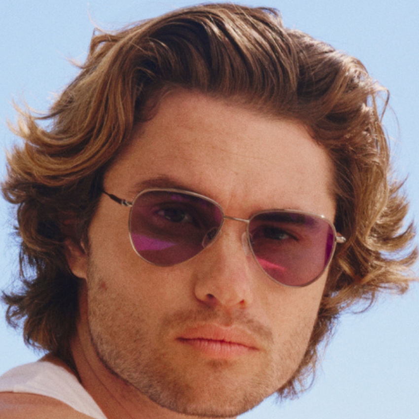 Man wearing aviator sunglasses with purple tinted lenses.