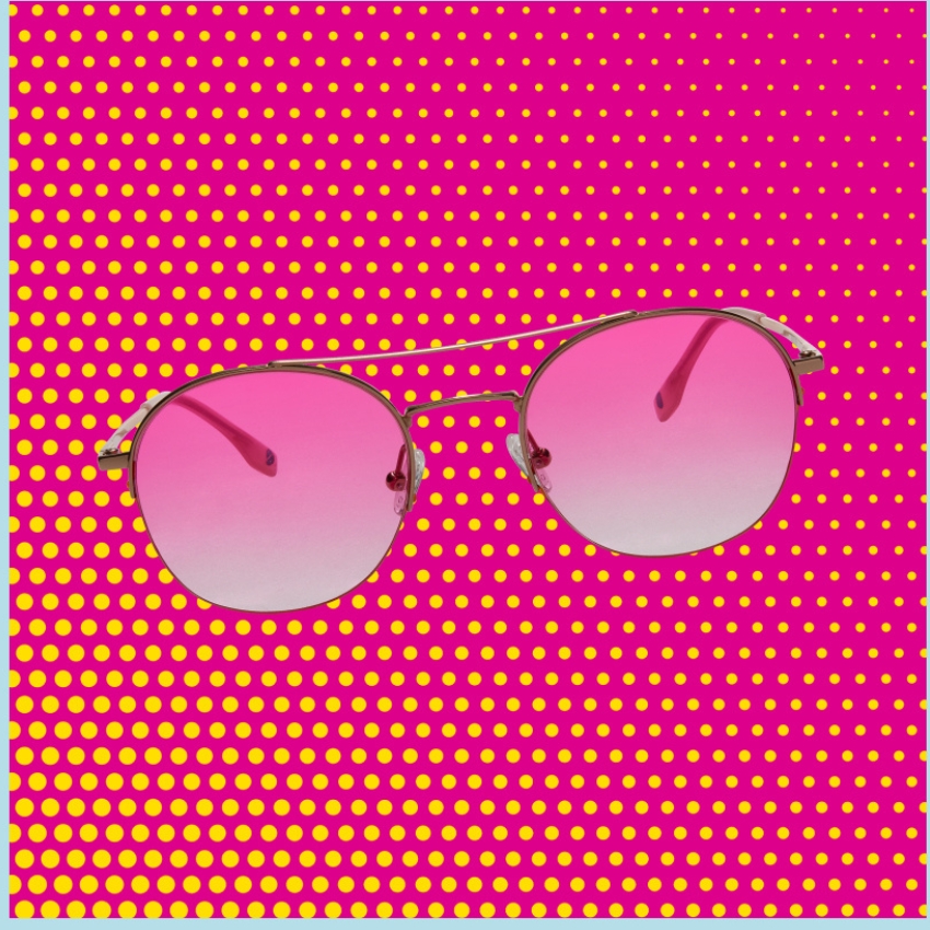 Pink gradient sunglasses with gold frames on a vibrant pink and yellow polka dot background.