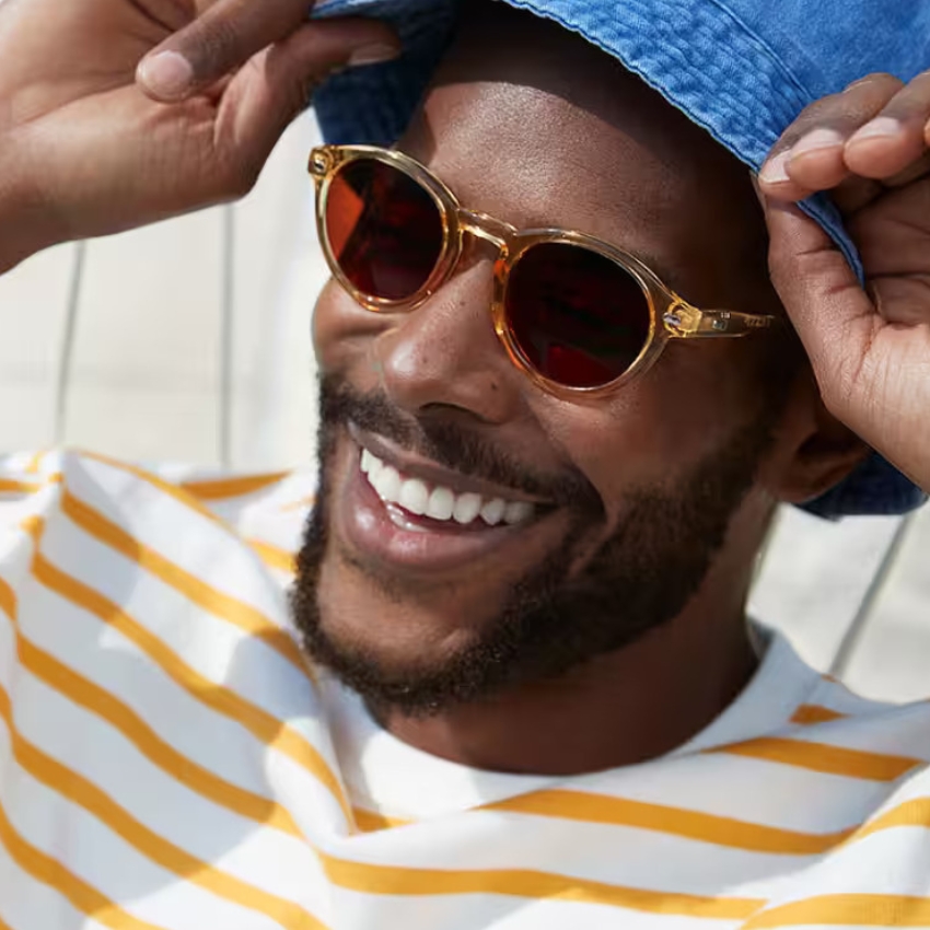 Smiling man wearing amber-colored sunglasses.