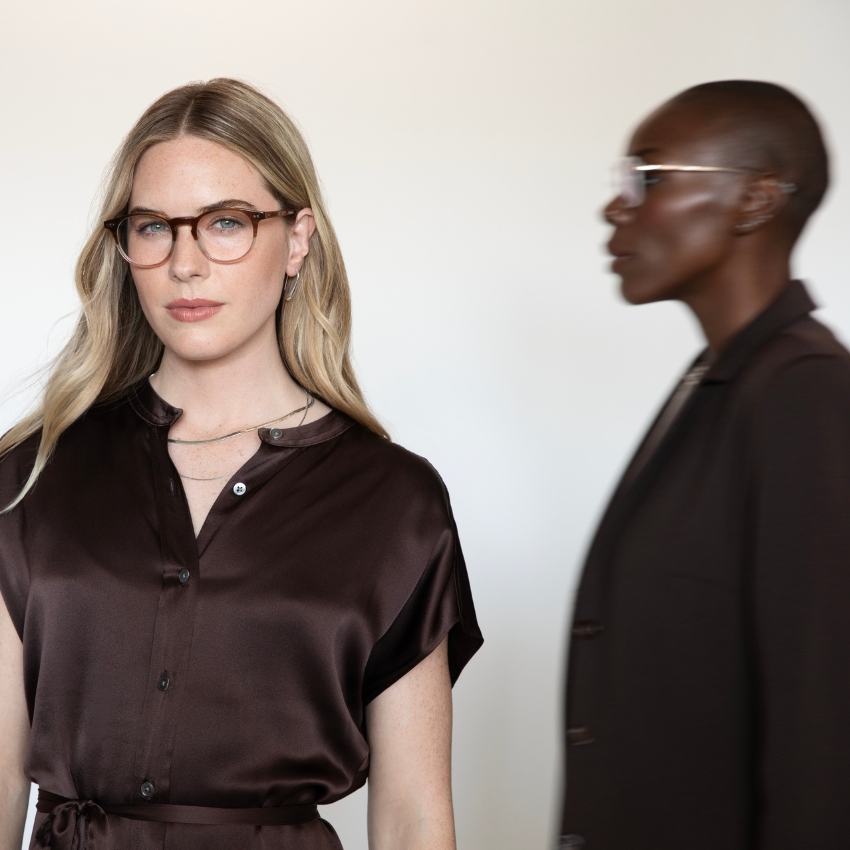 Blonde woman wearing brown eyeglasses and a dark brown satin blouse.