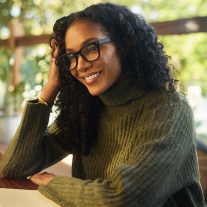 Woman with black-rimmed glasses wearing a green ribbed turtleneck sweater.