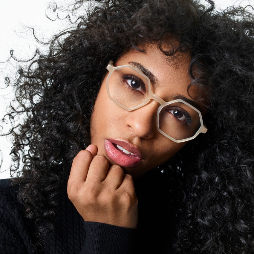 Translucent, hexagonal eyeglasses worn by a person with curly hair.