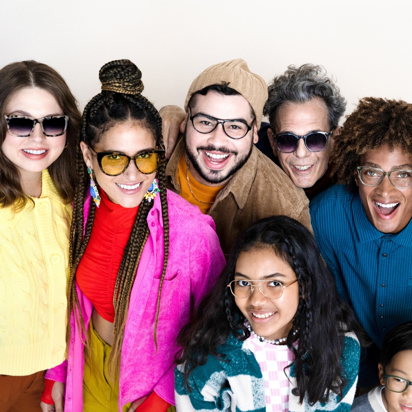 A group of people wearing various stylish eyeglasses, smiling cheerfully.