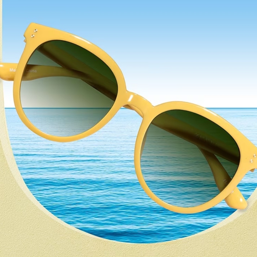 Yellow frame sunglasses with green lenses and ocean background.