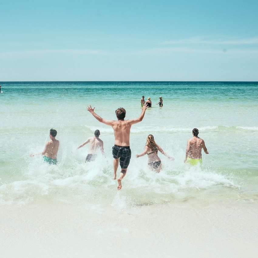 People running into the ocean waves on a sunny beach.