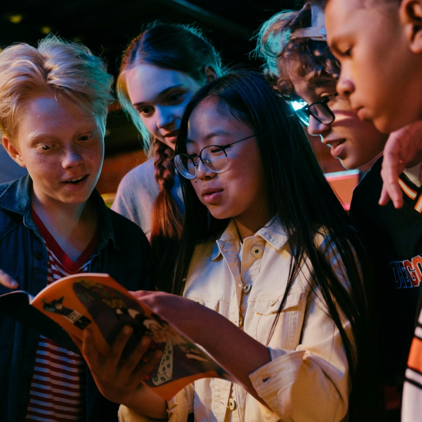 Children gathered around reading a comic book.