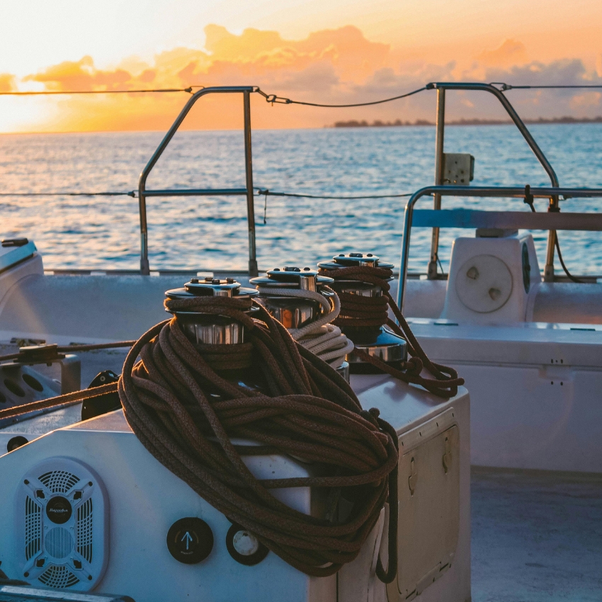 Boat winch with coiled ropes on deck at sunset.