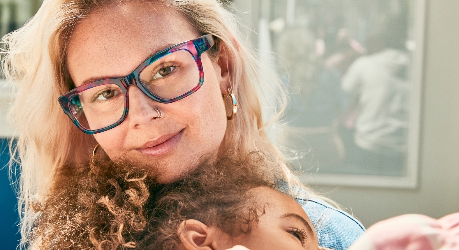 Woman wearing glasses holding a child