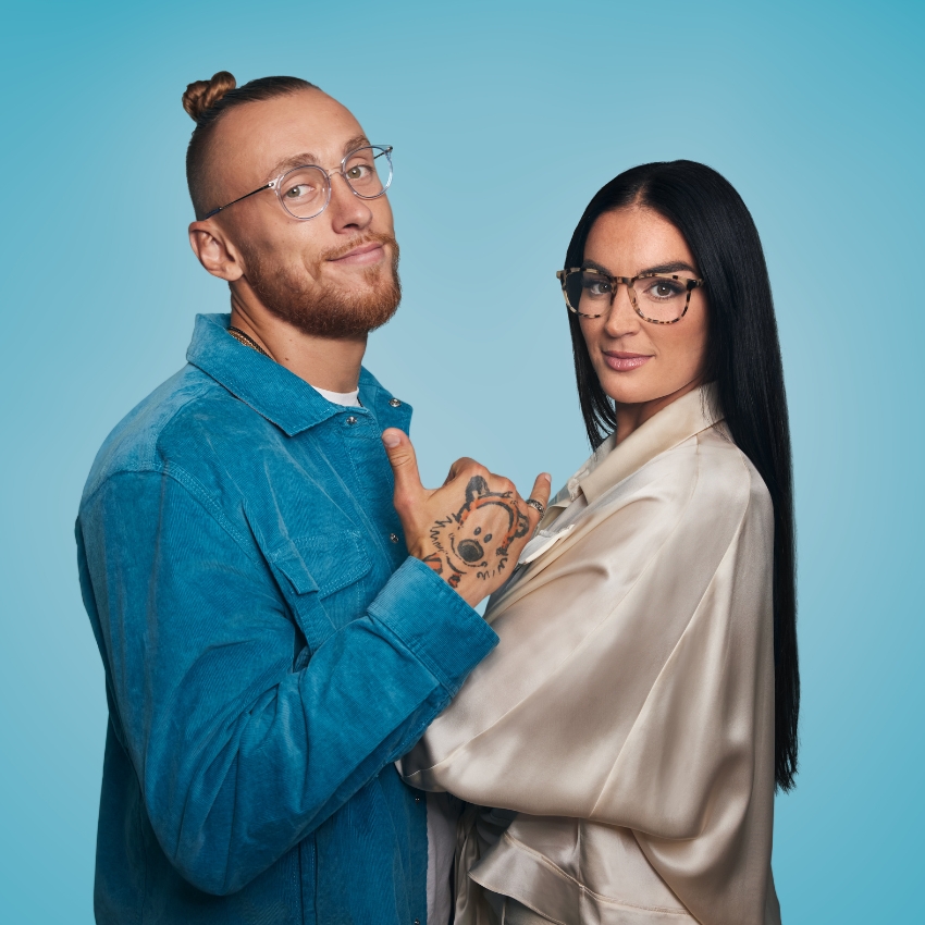 Man and woman wearing stylish eyeglasses; man has clear frames, woman has tortoiseshell frames.