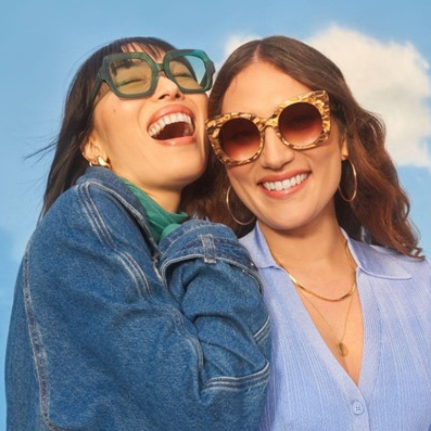 Two people wearing stylish sunglasses, one in oversized green frames, the other in tortoiseshell-patterned frames.