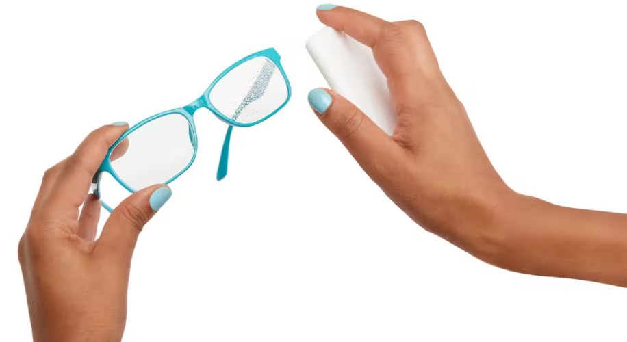 Person cleaning glasses with lens spray