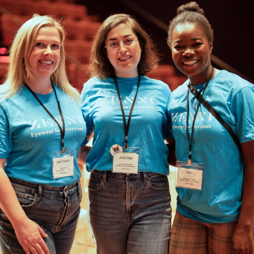 Three individuals wearing Zanmi t-shirts, "Eyewear for everyone," and name tags: BRITTANY, JUSTINE, TORI.