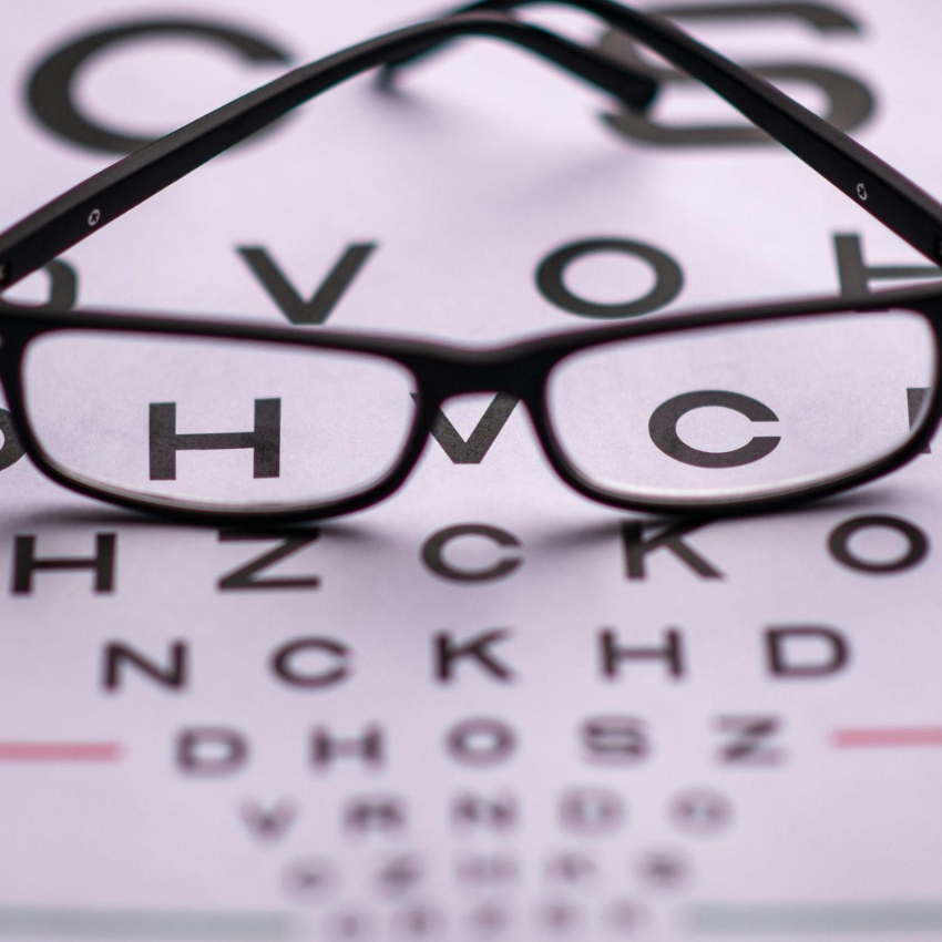 Black-framed eyeglasses placed on an eye chart with letters C, V, O, V, H, Z, C, H, V, C, K.